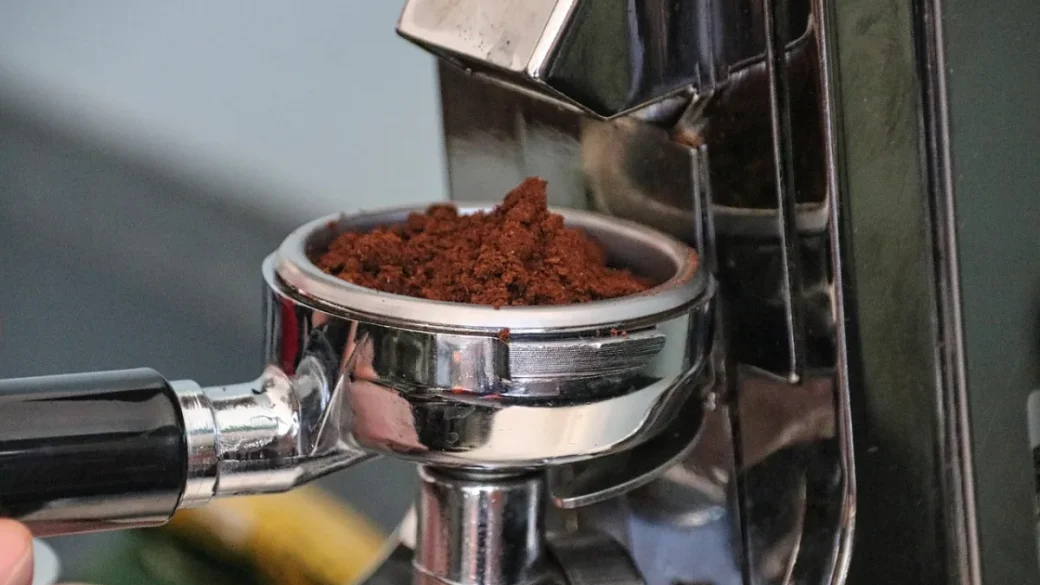 A conical burr grinder dosing ground coffee for espresso