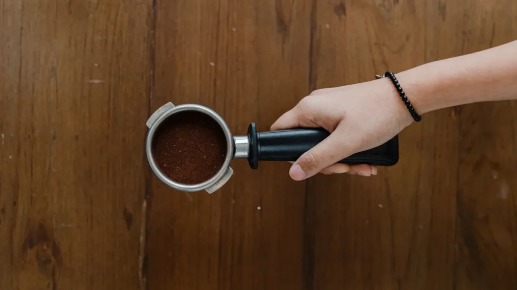 A portafilter and basket soaking in espresso detergent solution instead of the dishwasher