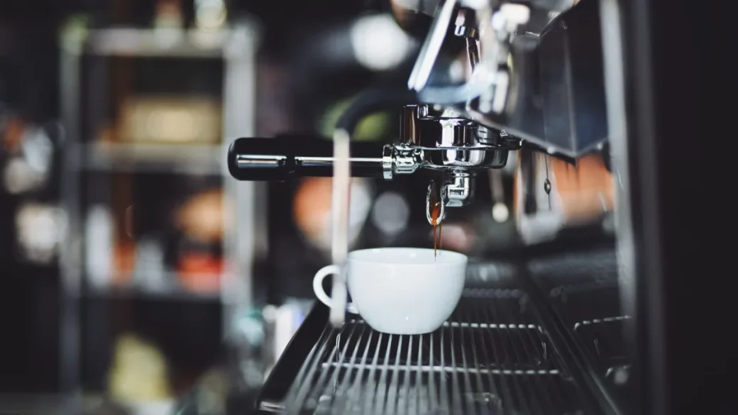 An espresso machine opened up on a repair bench showing the boiler and pump