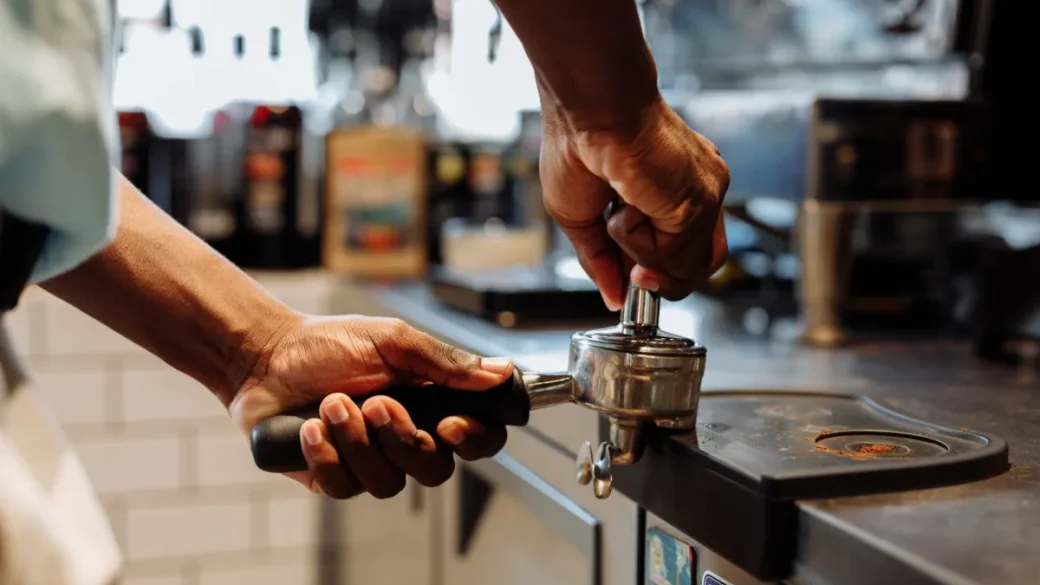 Tamping a level dose of espresso in a portafilter sitting on a coffee scale