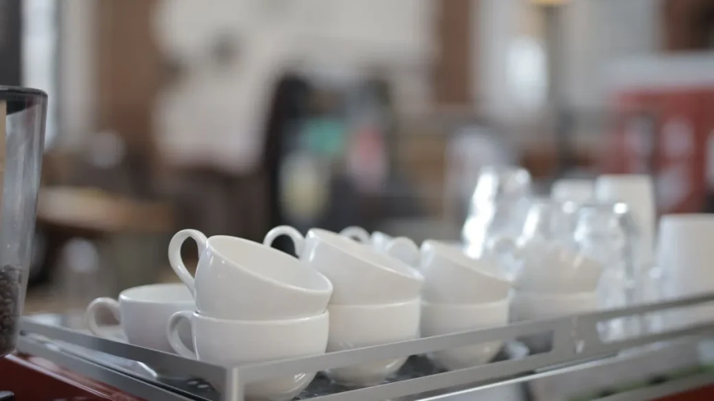 A bottomless portafilter showing an uneven, spraying espresso stream during channeling